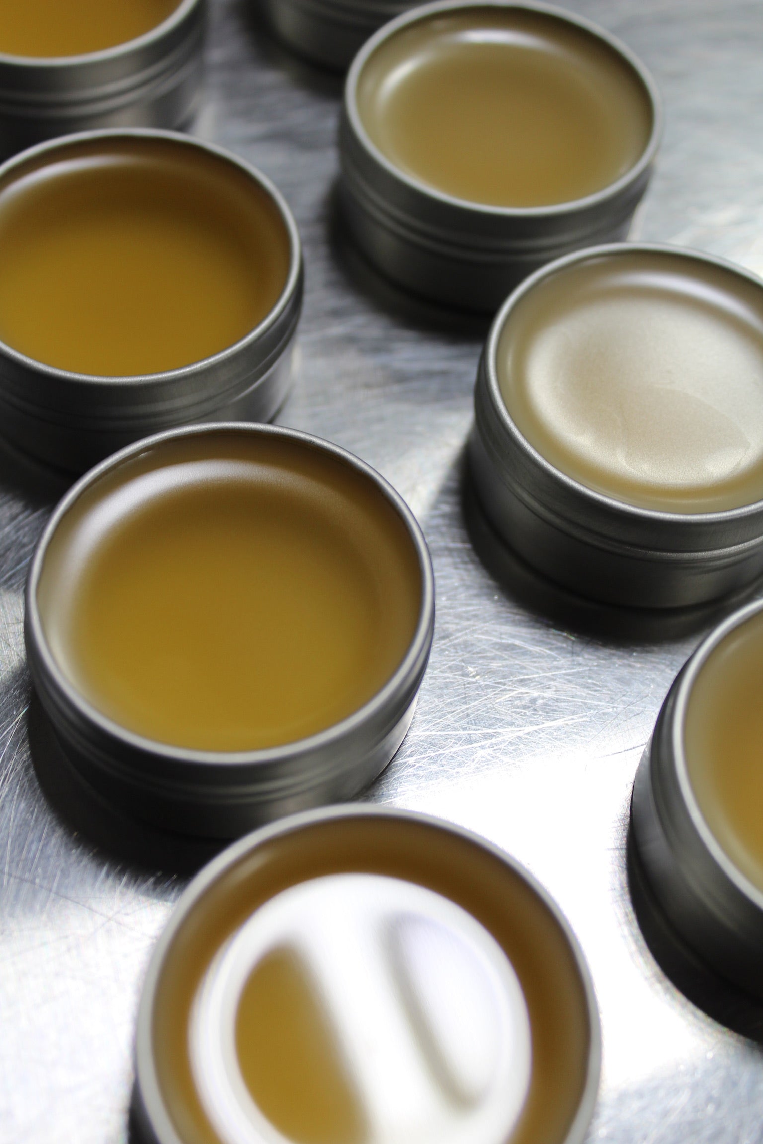 Collection of CBD products packaged in different glass bottles and boxes with fresh plant cuttings and cut fruit against a whitewashed wood background.