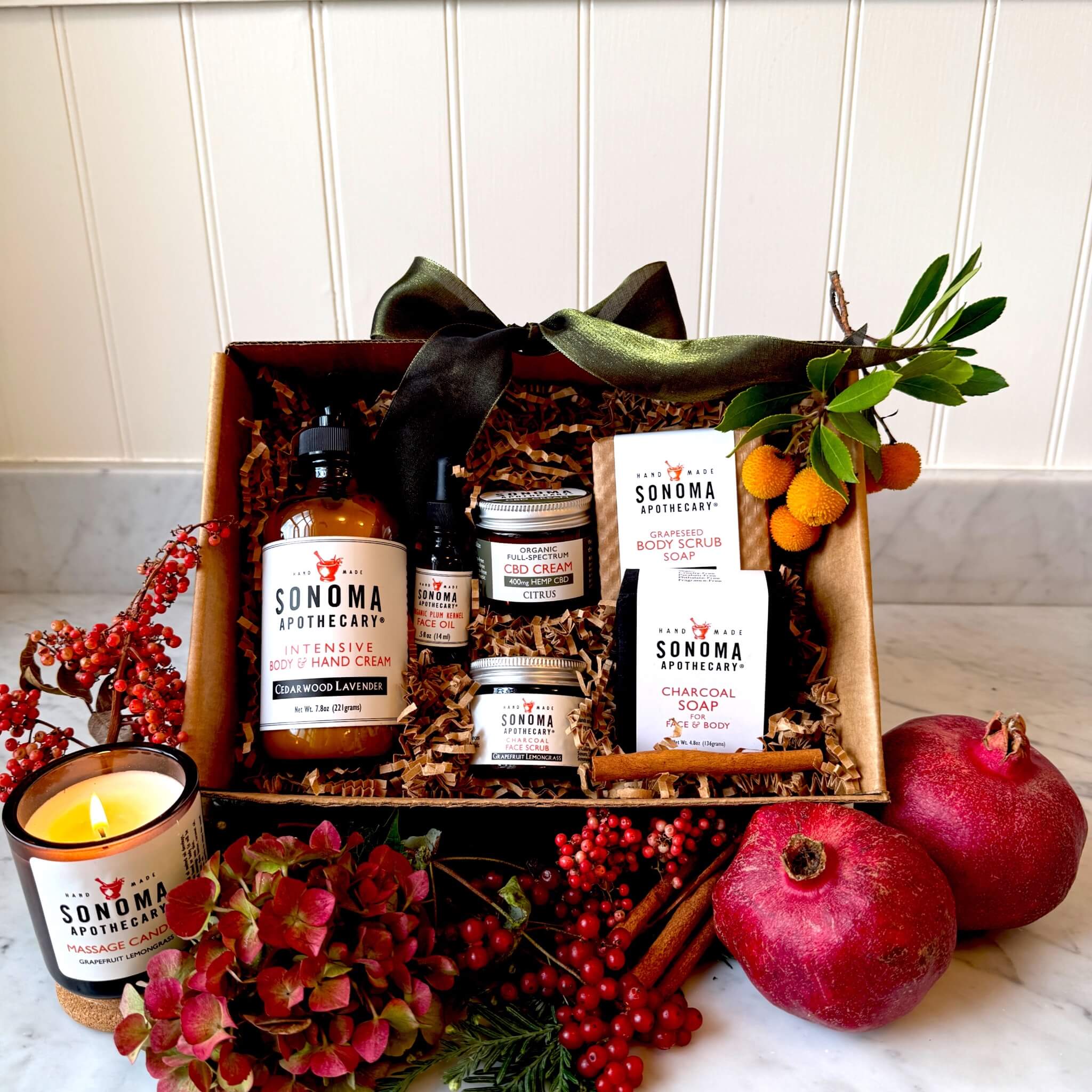 The Grand Ritual luxury gift set displayed decoratively in a box — includes lavender rosemary cream, citrus CBD cream, charcoal face scrub, face oil, body soaps, and grapefruit lemongrass candle for a restorative self-care experience.