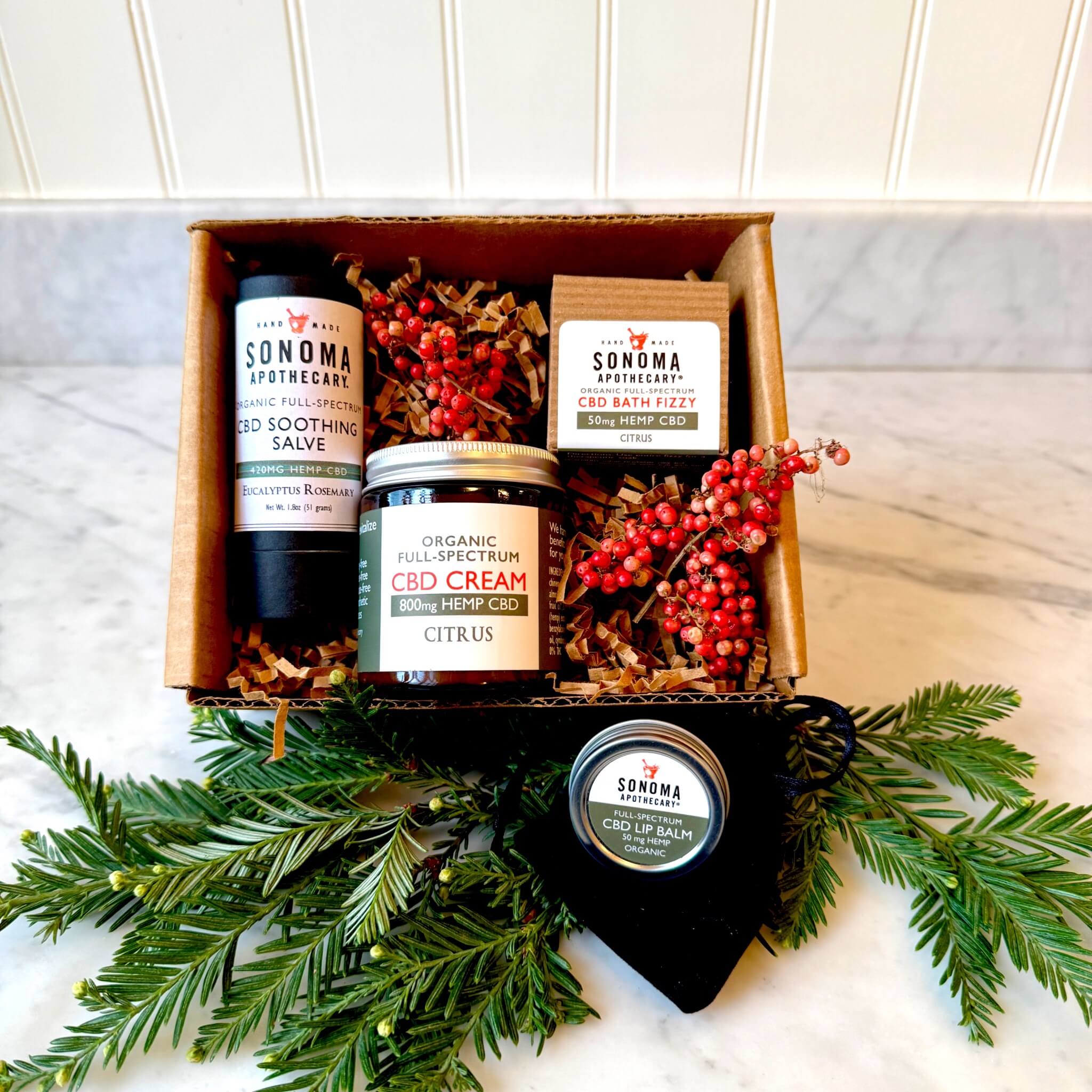 Recovery Mode CBD gift set displayed decoratively in a box — includes CBD cream, eucalyptus rosemary salve stick, bath fizzy, and unscented lip balm for soothing sore muscles and gentle body restoration.