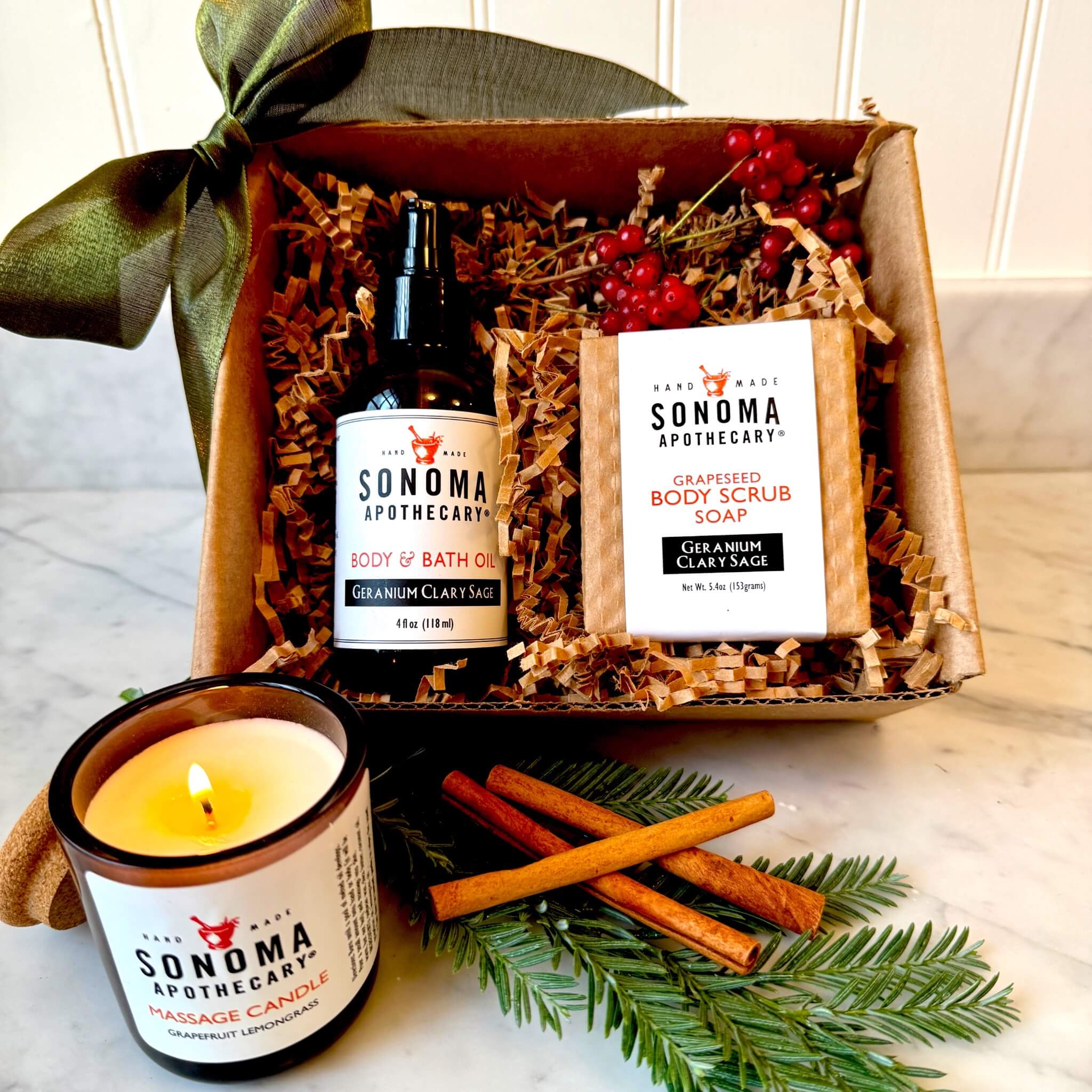 Do Not Disturb gift set displayed decoratively with a bow, evergreen, and cinnamon sticks — includes body oil, scrub soap, and grapefruit lemongrass candle for a cozy self-care night.